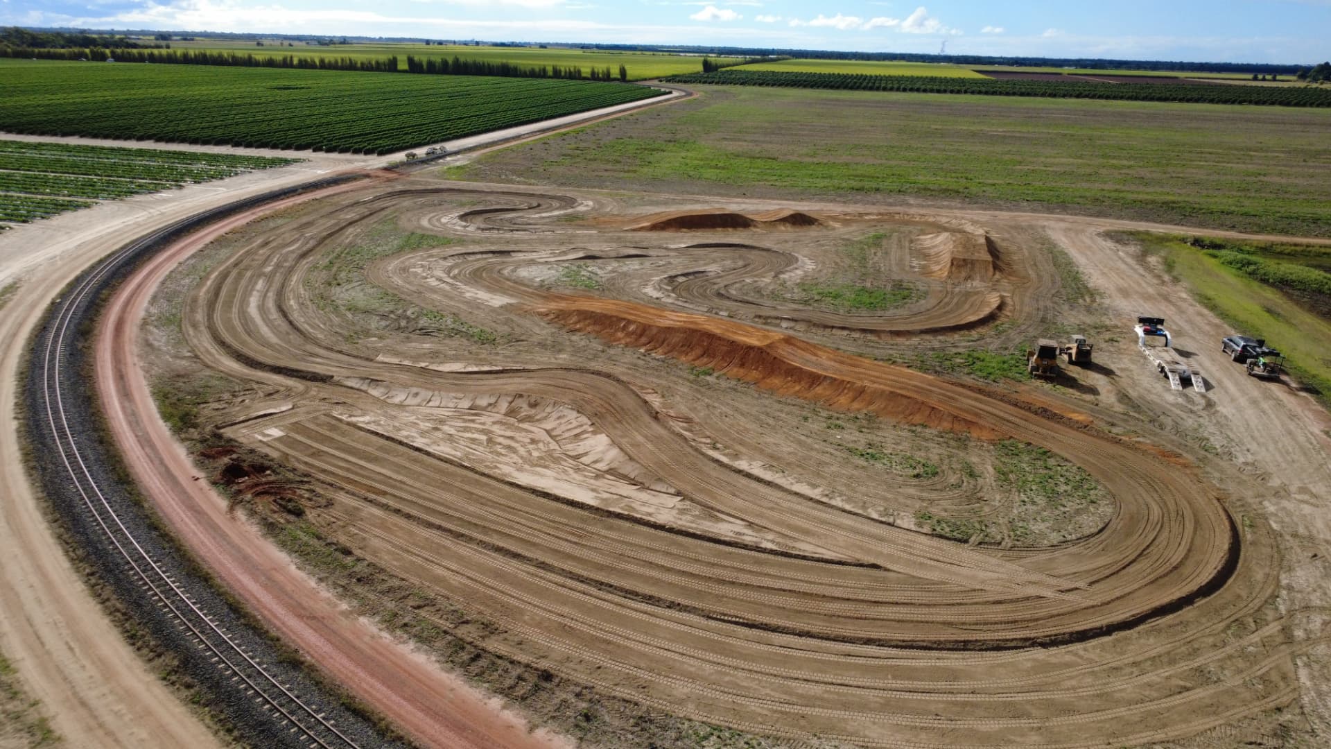 Aerial view of a private motocross track under construction beside farmland with a dozer on site